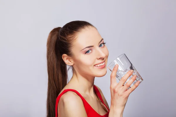 Beautiful young girl drinks water from glass — Stock Photo, Image