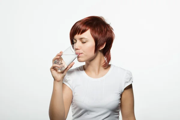 Tiener meisje drinking water uit glazen geïsoleerd op witte achtergrond — Stockfoto