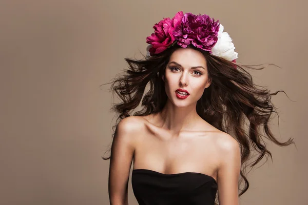 Mooie vrouw met heldere bloemen op haar hoofd — Stockfoto