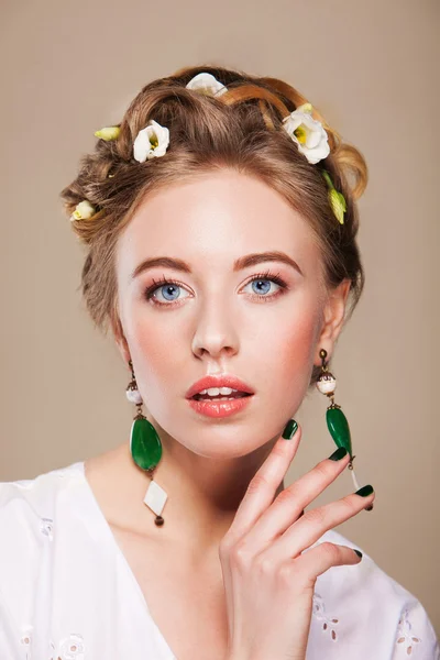 Kvinna med örhängen och blommor i håret — Stockfoto