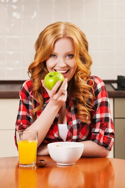 Woman eating a green apple in the kitchen Stock Photo