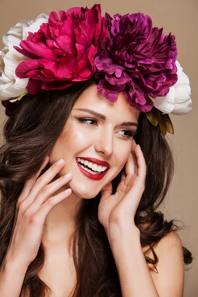 Beautiful smiling woman with bright flowers on her head. touching face — Stock Photo, Image