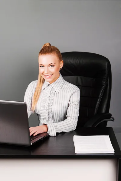 Feliz mujer de negocios sonriente escribiendo en el portátil en su escritorio — Foto de Stock