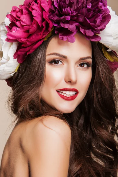 Vacker glad kvinna med ljusa blommor på hennes huvud och röda läppar — Stockfoto