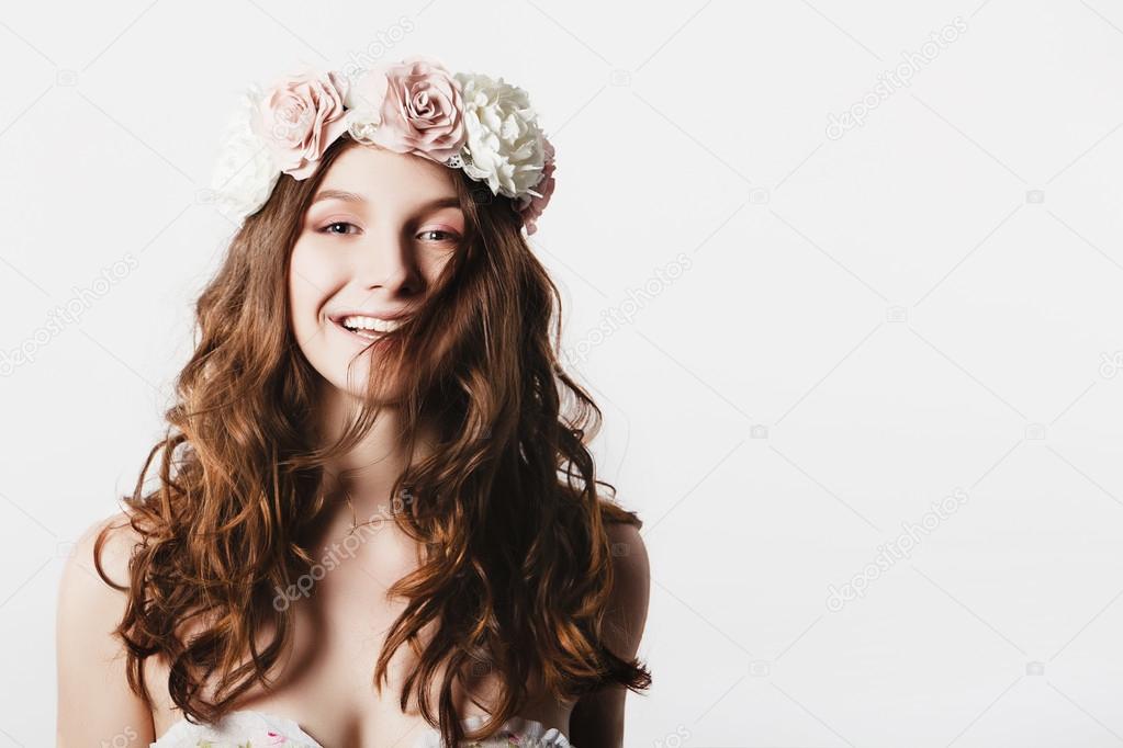 Beautiful happy young woman with delicate spring flowers in their hair