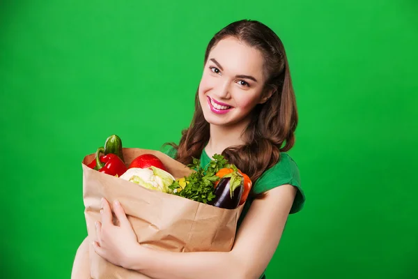 Bella donna che tiene una borsa della spesa piena di cibo fresco e sano. su sfondo verde — Foto Stock