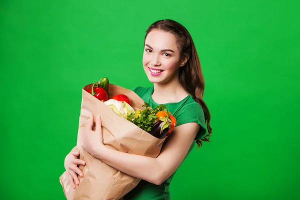 Mulher feliz segurando um saco de supermercado cheio de alimentos frescos e saudáveis. sobre fundo verde — Fotografia de Stock