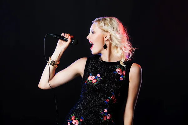 Mikrofon ile güzel şarkı söyleyen kadın. Şarkıcı. Karaoke şarkı. siyah arka plan üzerine