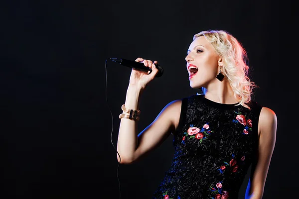 Beautiful blonde singing woman with microphone. Singer. Karaoke song — Stock Photo, Image