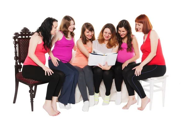 Sei donne incinte sorridenti sedute e leggendo un libro — Foto Stock