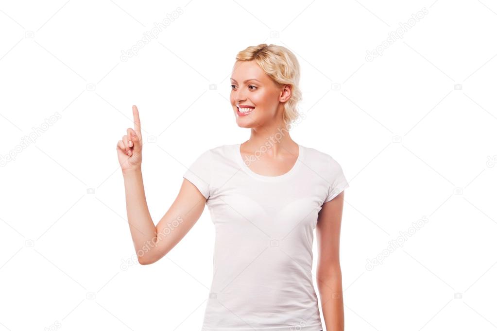 Young smiling woman with white t-shirt pointing up at copy space