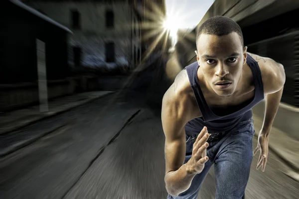 Jovem negro do sexo masculino correndo em um ambiente urbano — Fotografia de Stock