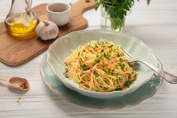 Taze pişmiş spagetti AGLIO E OLIO ve ahşap masadaki malzemeler
