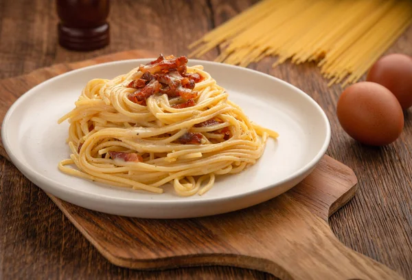 Mutfak masasında taze yapılmış spagetti carbonara tabağı