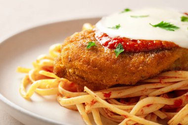 Parmesanlı tavuğu tabakta makarna ile kapat.