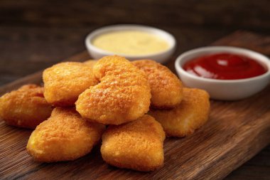 Yakın plan kesim tahtasında ev yapımı tavuk nugget ve soslar.