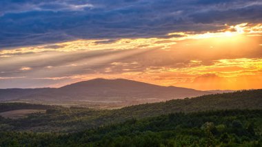 Güneş ışığı ve bulutlu gökyüzündeki dağ ormanları