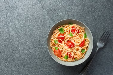 Spaghetti with cherry tomatoes top view with copy space on slate background