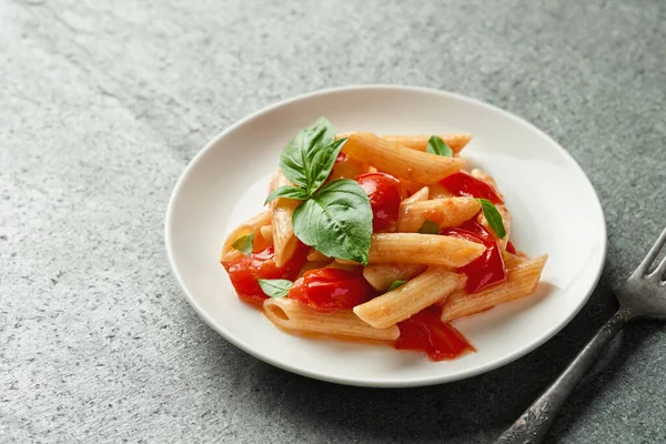 Close up plate of penne pasta with fried cherry tomatoes on gray slate background high angle view studio shot