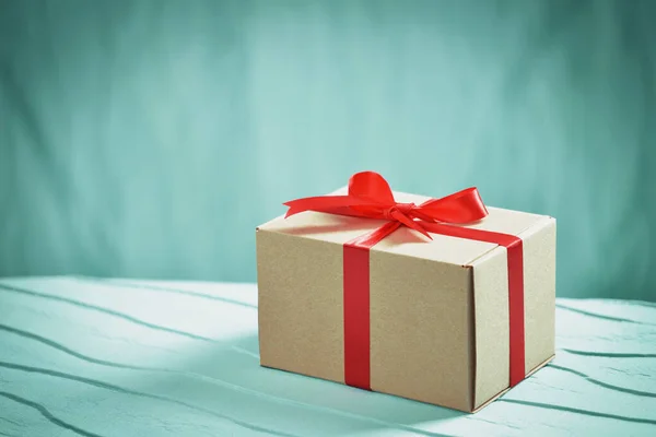 Kırmızı kurdeleli ve fiyonklu hediye paketi. Stüdyo yüksek bir açıdan çekim yapıyor. Kopyalama alanı ile.