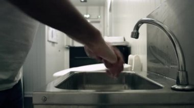Man washes his hands with towel. We can see the man taking a towel and drying his hands meticulously before throwing the towel into the trash can . Perfect health preventions