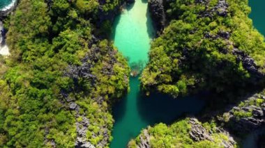 Aerial view with a drone over the Big Lagoon of El Nido in Philippines. We can see the lagoon in the middle of mountains under the blue sky 4K