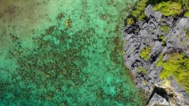 Kayak in the middle of the Big Lagoon of El Nido, Philippines. Perfect leisure for travel and paradise summer holidays under the sun - aerial view with a drone 4K