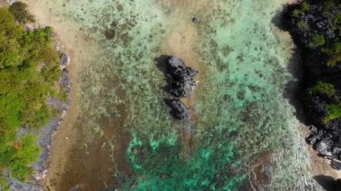Aerial view with a drone over a transparent blue lagoon in El Nido, Philipplnes. Beautiful landscape in paradise, perfect for travel in nature under the sun 4K