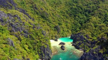 Turquoise lagoon surrounded by mountains and trees in El Nido, Philipplnes. Beautiful landscape in paradise, perfect for travel in nature under the sun - Aerial view with a drone 4K