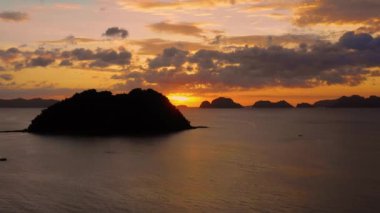 Aerial view of a small island in El Nido in Philippines under an orange sunset. Paradise landscape with only islands and South China Sea all over the horizon 4K