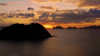 Aerial view of a small island in El Nido in Philippines under an orange sunset. Paradise landscape with only islands and South China Sea all over the horizon 4K