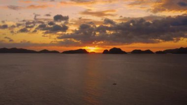 Island of El Nido in Philippines under an orange sunset. Paradise landscape with only islands and South China Sea all over the horizon - aerial view with a drone 4K