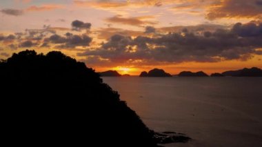 Aerial view of a small island in El Nido in Philippines under an orange sunset. Paradise landscape with only islands and South China Sea all over the horizon 4K