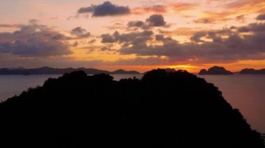 Island of El Nido in Philippines under an orange sunset. Paradise landscape with only islands and South China Sea all over the horizon - aerial view with a drone 4K