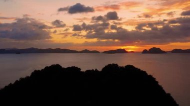 Island of El Nido in Philippines under an orange sunset. Paradise landscape with only islands and South China Sea all over the horizon - aerial view with a drone 4K