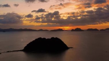 Filipinler 'deki El Nido adasının üzerinde turuncu gün batımı. Ufuk boyunca uzanan sadece adaları ve Güney Çin Denizi 'ni olan cennet manzarası. 4K insansız hava aracı ile hava manzarası.