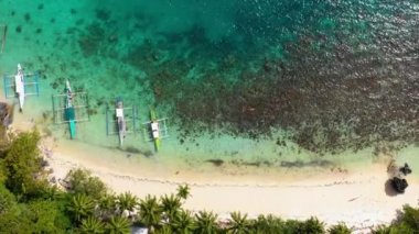 Aerial view over boats on El Nido beach, Philippines. Water is clear and turquoise near sand and palm trees, perfect for leisure activity in summer holidays 4K