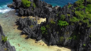 Aerial view with a drone over the Secret Lagoon of El Nido in Philippines. We can see people in the lagoon in the middle of mountains 4K