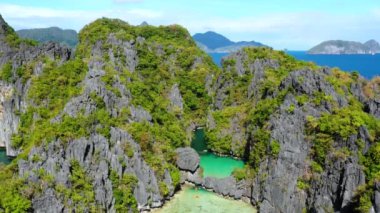 Aerial view with a drone over the Small Lagoon of El Nido in Philippines. We can see the lagoon in the middle of mountains under the blue sky 4K