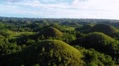 Filipinler 'deki Bohol' un Chocolate Hills üzerinde insansız hava aracı ile panoramik manzara. Güzel yeşil tepeler ve ağaçlar ufukta, mavi gökyüzünün altında - 4K