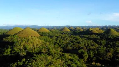 Filipinler 'deki Bohol' un Chocolate Hills üzerinde insansız hava aracı ile panoramik manzara. Güzel yeşil tepeler ve ağaçlar ufukta, mavi gökyüzünün altında - 4K