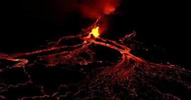 Panoramic view at dark night of an active volcano. The lava erupting through the crater and then flowing over the steep sides of the volcano. The camera zooming to show ash clouds and fast flowing rivers of glowing lava.