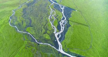 Aerial shot taken from above tracking interlinking small rivers.. Aerial shot taken from above tracking interlinking small rivers with grey silver water streaming over a riverbed all coated with moss and green grass. The shot shows vast green plain.