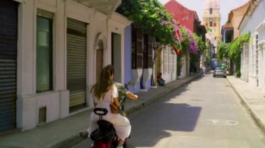 A couple on holiday in cartagena riding chopper in a narrow street.