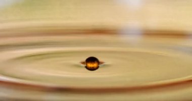 A closeup shot of brown coffee drops dripping inside a cup of coffee.