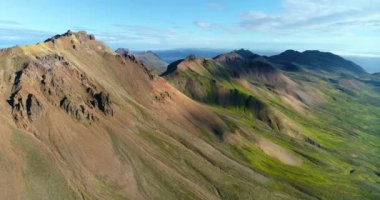 İzlanda 'daki panoramik manzara dağlık arazi ve eteklerdeki göl. Panoramik manzara canlı yeşil tepeler ve tepeler gösteriyor, ve tepeden akan muhteşem suyla küçük bir şelale ve dağ eteklerindeki güzel bir göle dökülüyor..