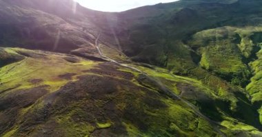 İzlanda 'daki panoramik manzara dağlık arazi ve eteklerdeki göl. Panoramik manzara canlı yeşil tepeler ve tepeler gösteriyor, ve tepeden akan muhteşem suyla küçük bir şelale ve dağ eteklerindeki güzel bir göle dökülüyor..