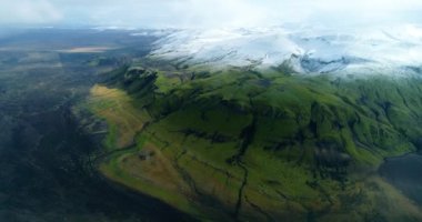 İzlanda 'daki panoramik manzara dağlık arazi ve eteklerdeki göl. Panoramik manzara canlı yeşil tepeler ve tepeler gösteriyor, ve tepeden akan muhteşem suyla küçük bir şelale ve dağ eteklerindeki güzel bir göle dökülüyor..