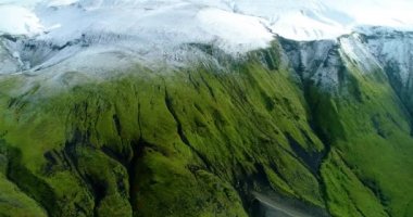 İzlanda 'daki panoramik manzara dağlık arazi ve eteklerdeki göl. Panoramik manzara canlı yeşil tepeler ve tepeler gösteriyor, ve tepeden akan muhteşem suyla küçük bir şelale ve dağ eteklerindeki güzel bir göle dökülüyor..