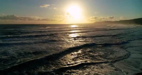 夕日の間にゆっくりとビーチを打つ海の波の空中ビュー 撮影は 海岸線を飛行し 地平線のいくつかの白い小さな雲を除いて ほぼ明確な空をキャプチャ無人機によって撮影されました — ストック動画